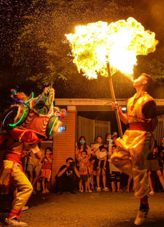circus artist, folk games, lion dance, mid-autumn festival, mid-autumn night, photo: unique lion dance, blowing fire like a circus performer on the mid-autumn festival night by young people in the suburbs of hanoi