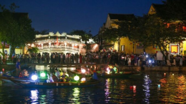 Tourists walk around Hoi An ancient town, waiting in long queues to drop flower lanterns on the Tet holiday