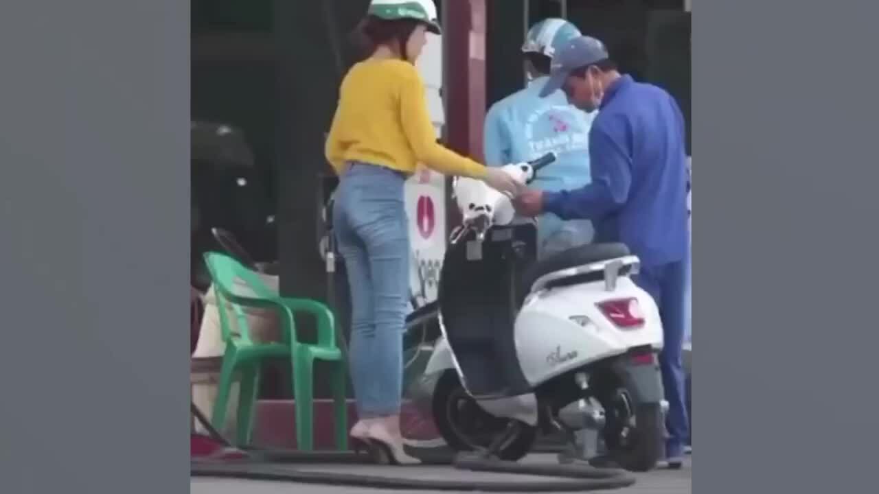 Cô gái dắt xe máy điện đi đổ xăng