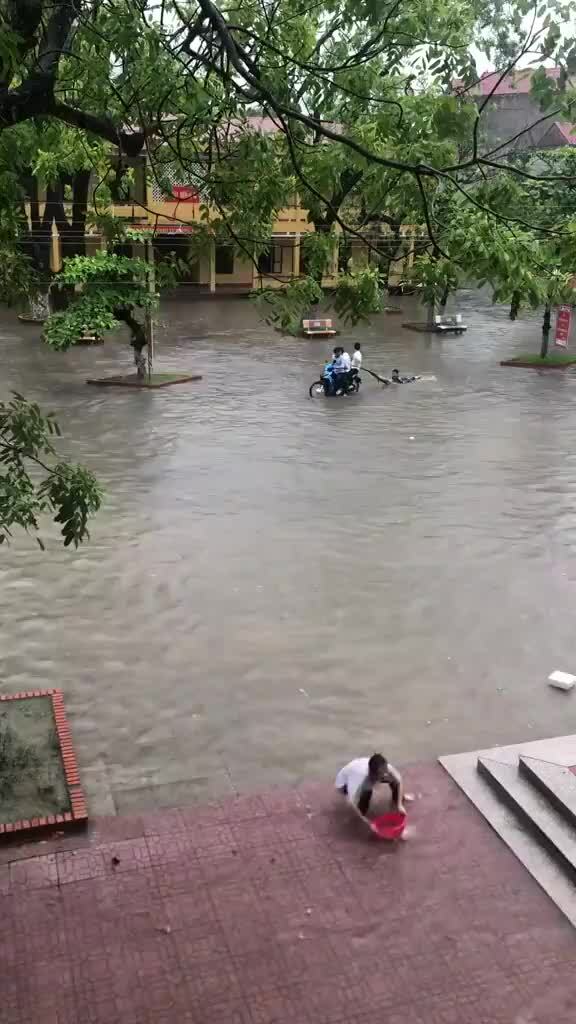 Học sinh lướt sóng trong sân trường sau mưa lớn